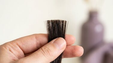 Mão segurando mechas de cabelo preto