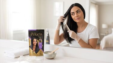 Mulher aplicando produto para cabelo em espelho