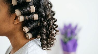 Mulher com cabelo cacheado usando bobes de cabelo.
