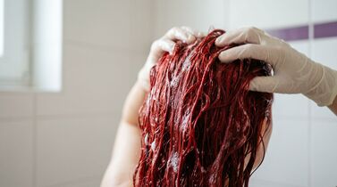 Pessoa aplicando shampoo em cabelo vermelho
