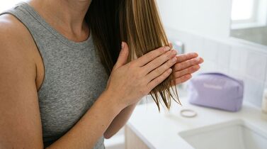 Mulher aplicando produto no cabelo em banheiro